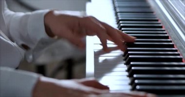 Kadın ya da Kız Öğrenci ya da Profesyonel Piyanist Güzel Beyaz Piyano 'da Klasik Müzik Çalıyor Noel ağacının arka planına karşı bir Noel Tatili ve yanıp sönen Yeni Yıl Işıkları. Piyanistlerin elleri.