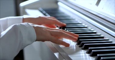 Kadın ya da Kız Öğrenci ya da Profesyonel Piyanist Güzel Beyaz Piyano 'da Klasik Müzik Çalıyor Noel ağacının arka planına karşı bir Noel Tatili ve yanıp sönen Yeni Yıl Işıkları. Piyanistlerin elleri.