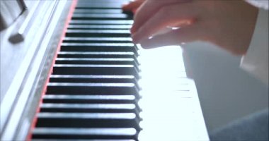 Kadın ya da Kız Öğrenci ya da Profesyonel Piyanist Güzel Beyaz Piyano 'da Klasik Müzik Çalıyor Noel ağacının arka planına karşı bir Noel Tatili ve yanıp sönen Yeni Yıl Işıkları. Piyanistlerin elleri.