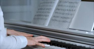 Kadın ya da Kız Öğrenci ya da Profesyonel Piyanist Güzel Beyaz Piyano 'da Klasik Müzik Çalıyor Noel ağacının arka planına karşı bir Noel Tatili ve yanıp sönen Yeni Yıl Işıkları. Piyanistlerin elleri.