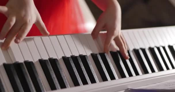 Little Baby Girl of Child Professional Pianist speelt klassieke muziek op een mooie witte piano een kerstvakantie tegen de achtergrond van een kerstboom en knipperende nieuwjaarslichten. Pianisten handen — Stockvideo