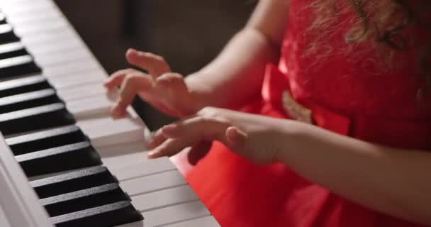 Little Baby Girl or Child Professional Pianist Plays Classical Music on a Beautiful White Piano a Christmas Holiday Against Background of a Christmas tree and Blinking New Year Lights. Manos de pianistas — Vídeos de Stock