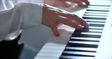 Kadın ya da Kız Öğrenci ya da Profesyonel Piyanist Güzel Beyaz Piyano 'da Klasik Müzik Çalıyor Noel ağacının arka planına karşı bir Noel Tatili ve yanıp sönen Yeni Yıl Işıkları. Piyanistlerin elleri.