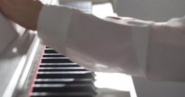 Kadın ya da kız A öğrencisi ya da profesyonel piyanist güzel beyaz bir piyanoda klasik müzik çalar. Yavaş çekimde piyanistin elleri. Piyano tuşları koyu renklerde kapanır. 4k