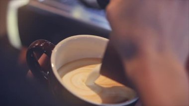 Profesyonel barista. Baştan sona kahve yapmak. Taze kahve doldurmak. Kahveye süt koyan barista latte sanatını yapıyor..