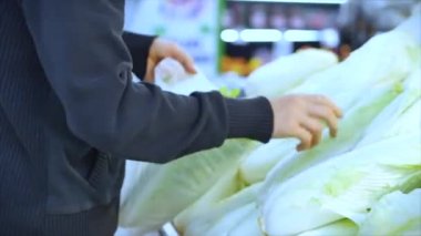 Man buys food, picks carrots, cabbage, lettuce, cauliflower in the market, in the supermarket.