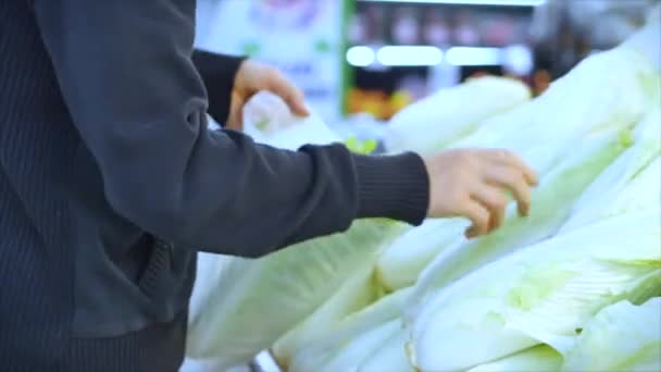 El hombre compra comida, recoge zanahorias, repollo, lechuga, coliflor en el mercado, en el supermercado . — Vídeos de Stock