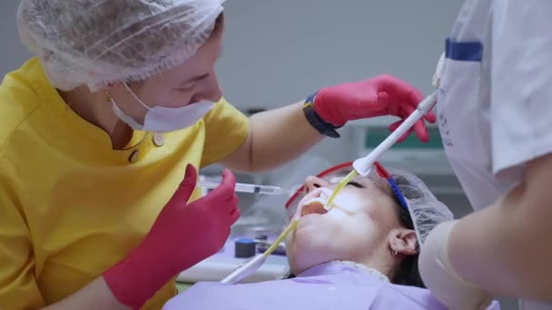 El médico o dentista profesional hace una inyección con una jeringa, inyecta un preparado con el paciente directamente en el canal dental . — Vídeo de stock