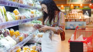 Güzel genç bir kız ya da kadın süpermarketten alışveriş yapar, yiyecek alır, marketten sağlıklı domatesleri seçer, süpermarketten. Alışveriş..
