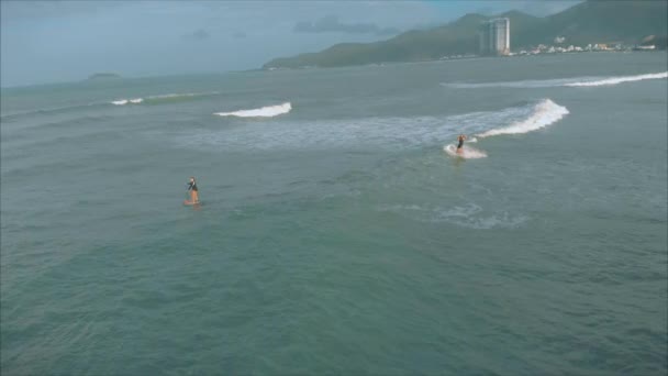 Sportowe młode kobiety i mężczyźni surfować, jeździć duże fale z jasnym świetle dnia, surfer czeka na jego fali. — Wideo stockowe