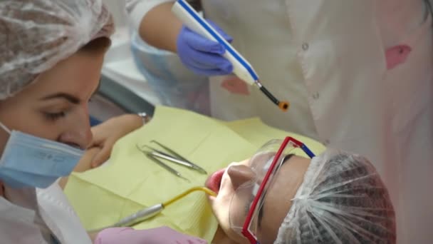 Professionell kvinnlig läkare tandläkare på jobbet, behandla tänder till kvinna patient på kliniken. Kvinnlig professionell läkare stomatolog på jobbet. Tandläkarutrustning på bakgrund. — Stockvideo