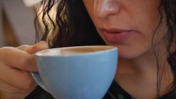 Nahaufnahme Porträt Junge hübsche Frau trinkt Morgenkaffee. Junges Mädchen im schönen sonnigen Tag trinkt Morgenkaffee in einem Café. — Stockvideo