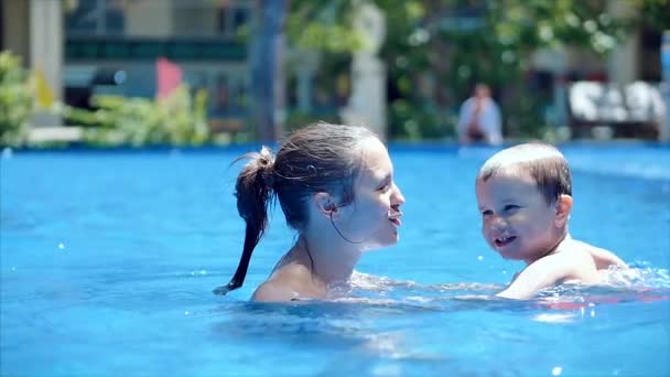 Roztomilý chlapeček a jeho matka mají lekci plavání v bazénu. Máma nebo chůva trenér drží v rukou svého syna On je objímá ho, učí plavání. Malý chlapec se šťastně usmívá, objímá maminku. — Stock video