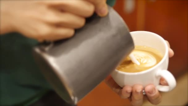 Професійний барист. Виготовляючи свіжу каву, бариста готує лате мистецтво заливання молока в чашку при створенні прекрасного малюнка, що робить каву ще більш бажаною.. — стокове відео