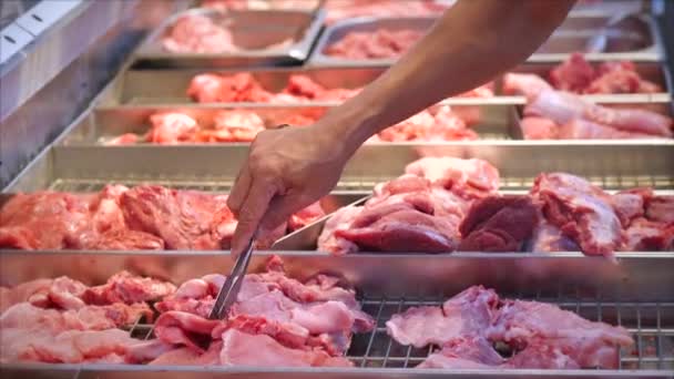 Человек покупает мясо, смотрит на куски мяса на курице собирает куски мяса щипцами на рынке, в супермаркете . — стоковое видео