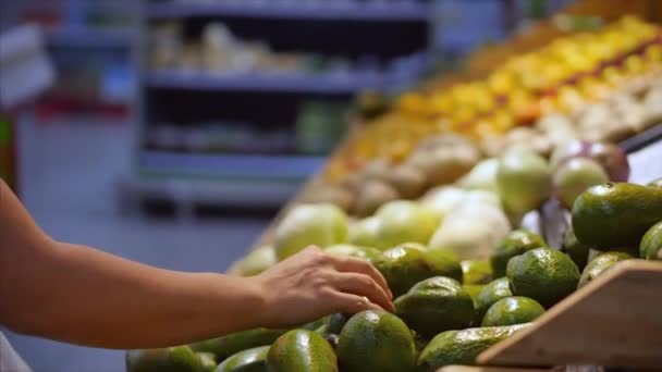 Mulher muito jovem ou mãe está fazendo compras no supermercado, escolhendo produtos no supermercado para cozinhar, alimentos saudáveis, abacates, frutas, laranjas no mercado, supermercado . — Vídeo de Stock