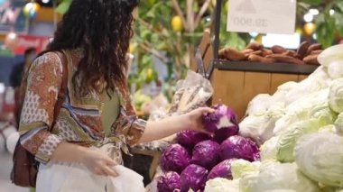 Güzel genç bir kadın süpermarketten alışveriş yapıyor. Marketten yemek, sağlıklı yiyecekler, lahana, karnabahar, süpermarket ürünleri seçiyor..