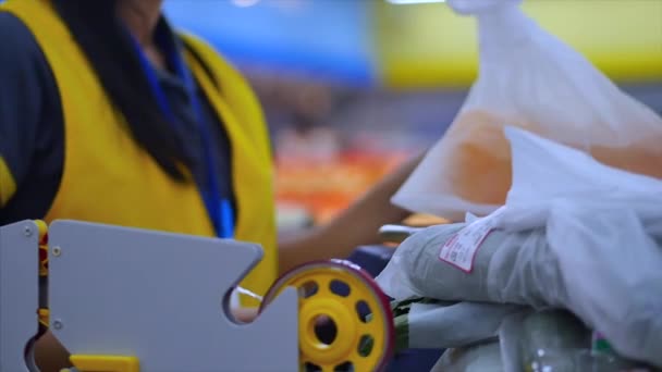 Caixa feminina ou uma vendedora em um supermercado ou no mercado faz com que os produtos cumprimentem nas balanças, enfia uma verificação no pacote com os bens, dá os produtos para o comprador . — Vídeo de Stock