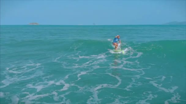 Surfer flies on the crest of a wave, a surfer controls the oar, standing on a surfboard. Surfer is waiting for his wave. — Stock Video