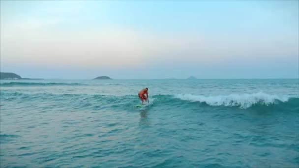 Surfer flies on the crest of a wave, a surfer controls the oar, standing on a surfboard. Surfer is waiting for his wave. — Stock Video