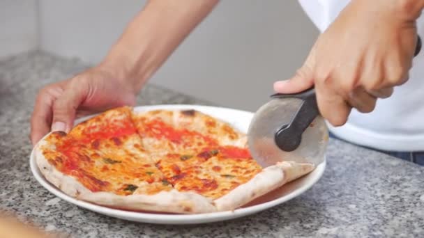 焼きたての薪焼きピザはスライスされ、メルティーチーズで提供されています.映像焼きたての木のピザピザカッターで複数のスライスにペパロニピザをスライス. — ストック動画