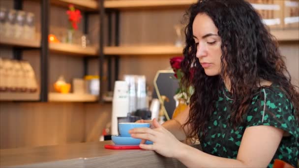 Jonge vrouw in mooie zonnige dag drinkt 's morgens koffie in een café, waardoor Online een aankoop gemakkelijk betalen op het internet met behulp van een mobiele telefoon of laptop. — Stockvideo