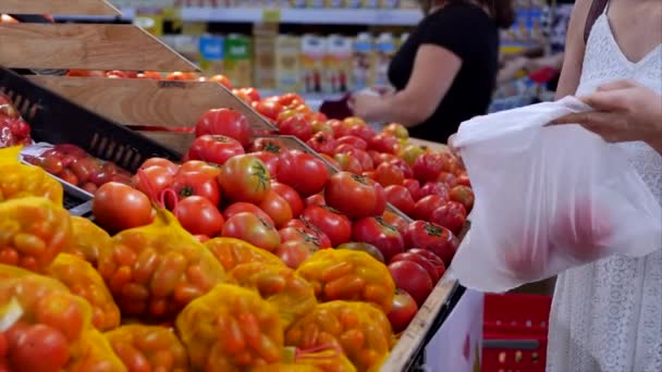 Mulher está fazendo compras no supermercado, escolhendo produtos no supermercado para cozinhar, alimentos saudáveis, tomates, abacates, frutas, laranjas no mercado, supermercado . — Vídeo de Stock