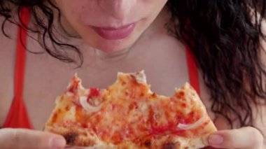 Kırmızı elbiseli, genç, tatlı İtalyan görünümlü bir kadın restoranda İtalyan pizzası yiyip eğleniyor. Kadın yiyeceği, besin, kalori kavramı.