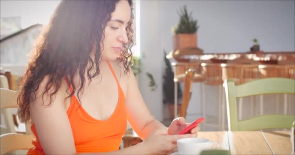 Junges Mädchen oder Frau beim Kaffeetrinken im Cafe beim Teilen von Nachrichten in den sozialen Medien mit Freude an mobiler Technologie. — Stockvideo