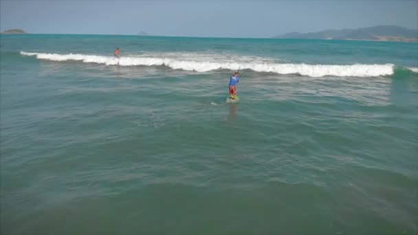 A szörfös várja a hullámát. Egy szörfös repül a hullám tetején, egy szörfös irányítja az evezőt, egy szörfdeszkán áll.. — Stock videók