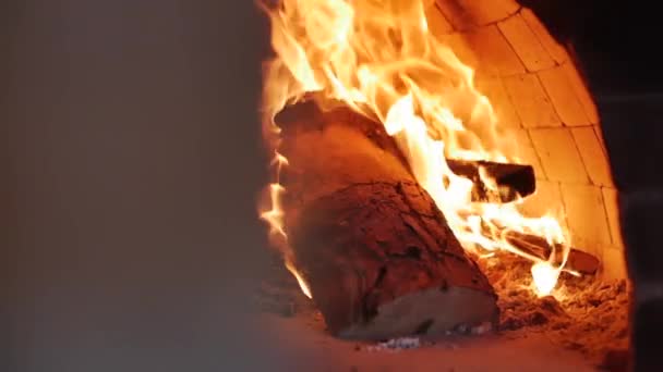 Mouvement sur le curseur. Gros plan sur le bois carbonisé brûle parfaitement dans un four à pizza. Placer la pizza dans un four à pizza au feu de bois à l'aide d'une croûte de pizza. Mouvement lent . — Video