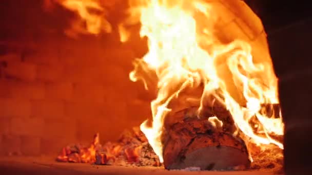 Close-up als in een pizza oven verbrandt vers vers gegooid brandhout prima. Plaats de pizza in een houtoven met de pizzaschillen. Langzame beweging — Stockvideo