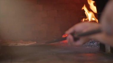 Pizzacı Usta gerçek bir İtalyan pizzası yapıyor pizzayı pizza kabuğunu kullanarak fırından çıkararak hazır olup olmadığını kontrol ediyor..