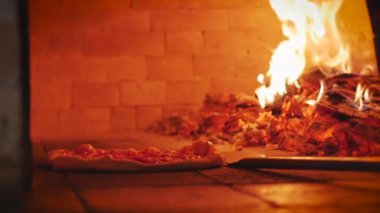 Pizzacı Usta gerçek bir İtalyan pizzası yapıyor pizzayı pizza kabuğunu kullanarak fırından çıkararak hazır olup olmadığını kontrol ediyor..