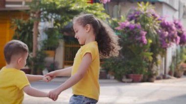 Aktif kız ya da kız kardeş dadı ve küçük tatlı erkek bebek el ele tutuşarak dans ediyorlar, mutlu aile kızı ve oğlu, çocuklar birlikte eğlenceli aksiyon oyunları oynuyorlar..