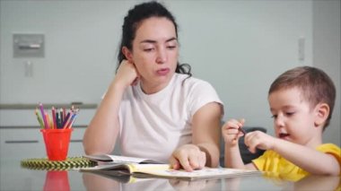 Mutlu aile annesi, dadı evde masa oyunu oynayan sevimli çocuğu öğreniyor, anne bebeğe kalemlerle resim çizmeyi öğrenmesinde yardımcı oluyor, yaratıcı sürecin tadını çıkarıyor..