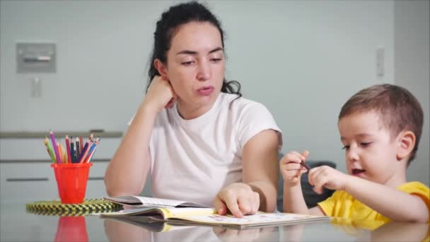 Glückliche Familienmutter Kindermädchen lernen niedlichen Jungen Brettspiele zu Hause, hilft Mutter Baby Sohn lernen, mit Bleistiften zusammen zu zeichnen genießen den kreativen Prozess. — Stockvideo