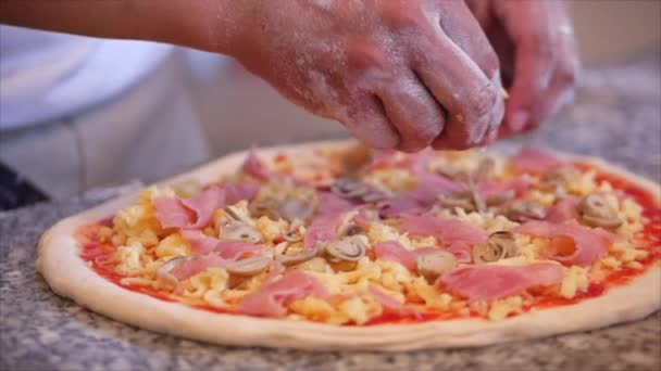 Vera pizza al salame piccante, metodo di cottura, cuoco italiano fa vera pizza italiana dall'impasto con le dita, spruzza fette di salsiccia affumicata sulla pizza . — Video Stock