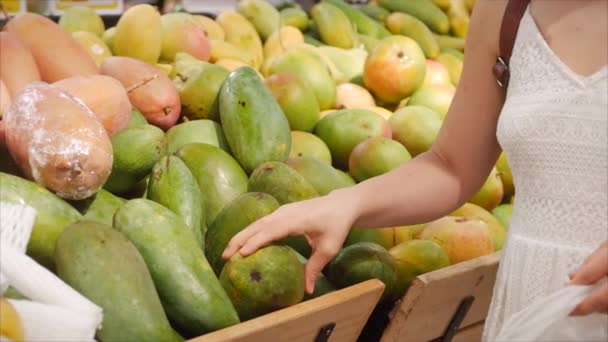 Güzel genç bir kadın süpermarketten alışveriş yapıyor. Marketten yemek, sağlıklı yiyecekler, mango, süpermarket ürünleri seçiyor.. — Stok video