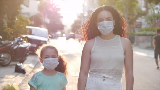 A mãe e a filha estão de pé em uma rua em máscaras protetoras da epidemia de Covid-N1H1. Conceito de Saúde e Segurança da Vida, Covid-19, Proteção de Vírus, uma pandemia na Palavra. Coronavírus N1H1 — Vídeo de Stock