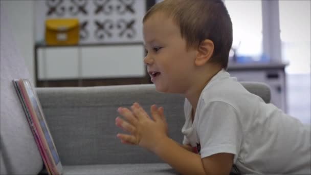 Curiosa niña linda preescolar utilizando tableta digital dispositivo de tecnología que se encuentra en el suelo de la alfombra solo. Pequeño niño mantenga la computadora de la almohadilla de navegación juego de Internet en casa. Concepto de adicción tecnológica infantil — Vídeo de stock