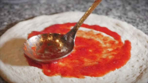 Método de cozimento pizza pepperoni, chef italiano faz verdadeira pizza italiana, derrama um molho vermelho especial sobre a massa com uma concha e rola-lo em um movimento circular . — Vídeo de Stock