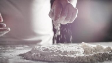 Profesyonel bir mutfakta İtalyan şef İtalyan pizzası yapmak için hamuru unla hazırlıyor..