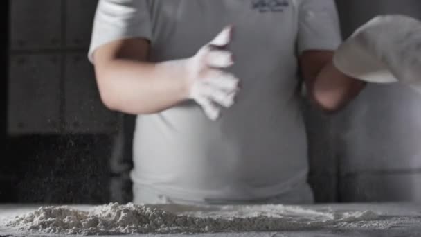 面粉从一个意大利厨师手中掉下来，他在一个专业厨房里用面粉做意大利比萨饼. — 图库视频影像