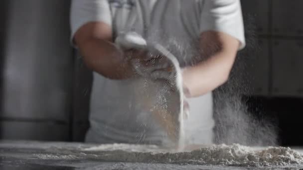 Farinha cai das mãos de um chef italiano em uma cozinha profissional preparando uma massa com farinha para fazer pizza italiana. — Vídeo de Stock