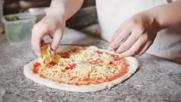 Echte peperoni pizza, kookmethode, Italiaanse chef-kok bereidt echte Italiaanse pizza, strooit pizza met parmezaanse kaas. — Stockvideo