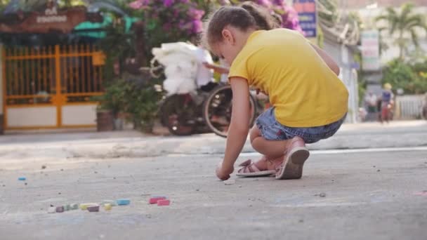 Αστεία μικρά παιδιά, παιδιά προσχολικής ηλικίας παίζουν, κάνουν σχέδια με χρωματιστά μολύβια μαζί, ζωγραφίζουν με χρωματιστά μολύβια κραγιόνια στην άσφαλτο στο δρόμο. — Αρχείο Βίντεο
