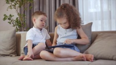Şirin bir aile ve kız kardeş, küçük kardeşi olan bir dadı, cep telefonundaki tablete bakıyor, kız ve erkek kardeşi kanepede oturuyor, akıllı telefonlarıyla oynuyorlar..