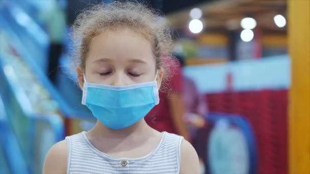 La bambina carina da un'epidemia di coronavirus o virus guarda la macchina fotografica tra la gente in maschere dal virus che scendono su una scala mobile nella metropolitana. Corontin, isolamento delle persone . — Video Stock