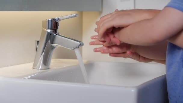 Matka matka myje ręce swojego syna wodą z mydłem, aby zapobiec pandemii koronawirusa myjąc ręce mydłem i ciepłą wodą, i zabijając drobnoustroje żelem dezynfekującym. — Wideo stockowe
